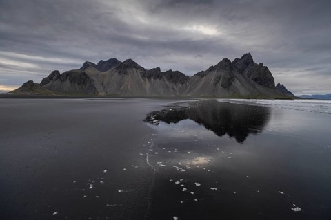 Vestrahorn, mountains with black lava sand, reflection in the water, south coast of Iceland