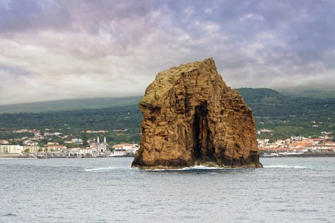 The majestic rock 'Iieu em Pe' rises from the sea, background with Pico Island and the town of