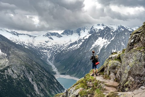 Mountaineer on hiking trail, view of Schlegeisspeicher, glaciated rocky mountain peaks Hoher