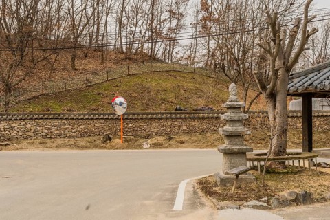 Five story concrete pagoda next to tree with trimmed branches in public park on corner of rural