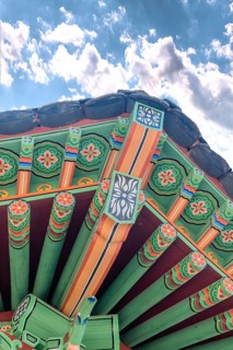 Colorful eves of oriental gazebo on hill in nature park on cloudy afternoon