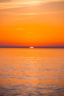 Intense, atmospheric sunset with bright orange-yellow sky over the Baltic Sea, only a small part of