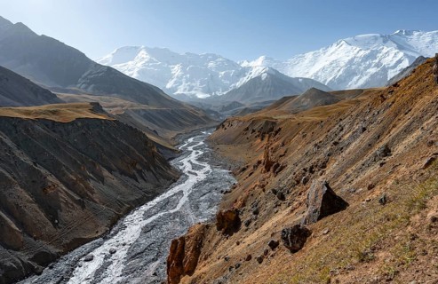 Achik Tash river, Achik Tash valley with rock formations, behind glaciated and snow-covered
