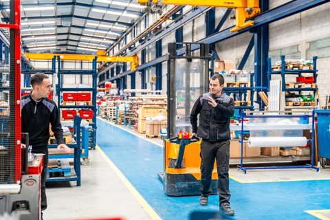 Coworkers taking while using handcart in a logistic center