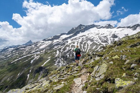 Mountaineer on rocky hiking trail, Berliner Hoehenweg, mountain landscape with snow-covered peak