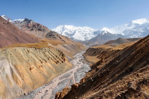 Achik Tash river, Achik Tash valley with rock formations, behind glaciated and snow-covered