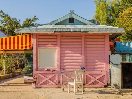 Pink wooden building with yellow and red awning and white roof at bankrupt amusement park