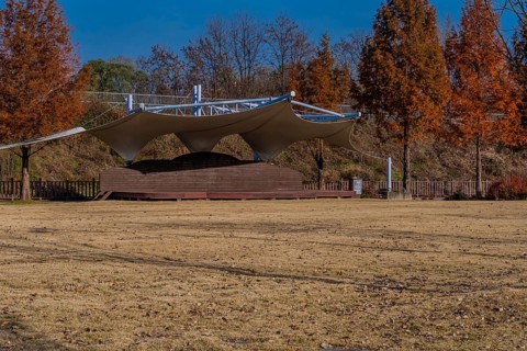 Outdoor event and performance stage with white canvas awning located in public park