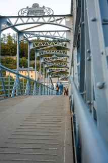 People walking across an ornate steel bridge in an urban area, Mozartsteg, Salzburg, Austria,
