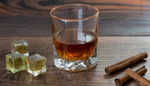 Whiskey with rocks or ice cubes in a glass with ice in a dark wooden background. AI Generated, AI