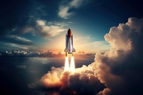 Aerial view of a rocket shuttle carrier launch at sunrise over an ocean coast. The rocket is