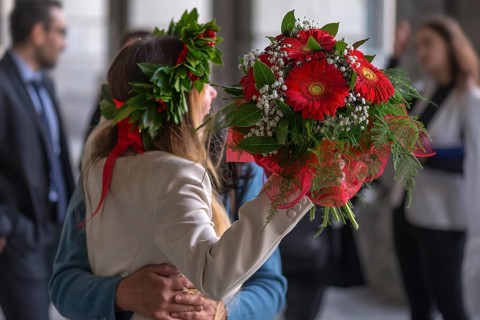 Joyful graduate of the University of Genoa with traditional laurel wreath and red ribbon and