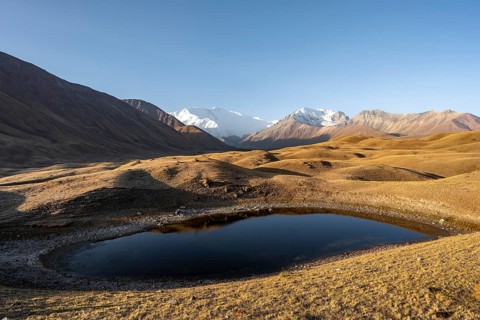 White glaciated and snow-covered mountain peak Pik Lenin at sunrise, mountain landscape with golden