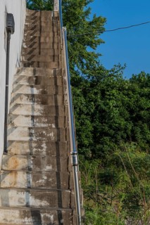Outside staircase going up to roof of white field in field under blue sky