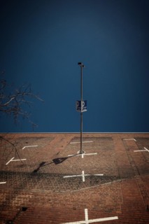 Lighting column and car park sign cast a shadow on a large brick wall, Cologne Deutz, North