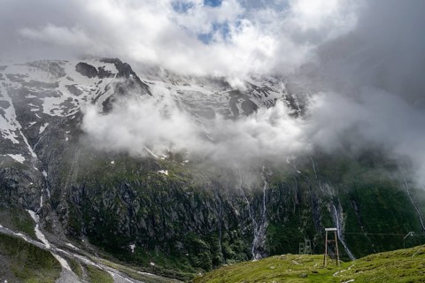 Snow-covered cloudy mountains with summit Hochsteller, mountain streams as waterfalls on a