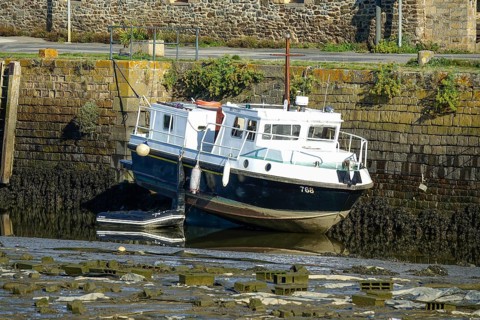 Boat lying on dry land at low tide on the Riviere du Faou on the Rade de Brest, Le Faou, Finistere