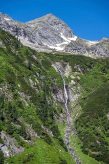 Waterfall of a mountain stream Kesselbach, rocky mountain peak, Berliner Hoehenweg, Zillertal Alps,