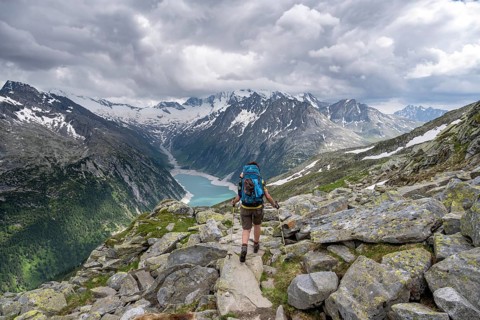 Mountaineer on hiking trail, view of Schlegeisspeicher, glaciated rocky mountain peaks Hoher