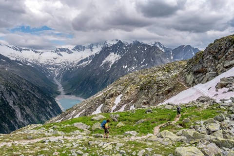 Two mountaineers on hiking trail, view of Schlegeisspeicher, glaciated rocky mountain peaks Hoher