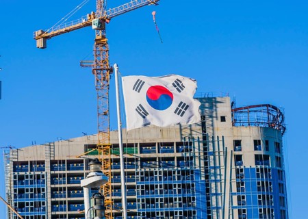 Korean flag on flying from a ship with a construction crane attached to a building under