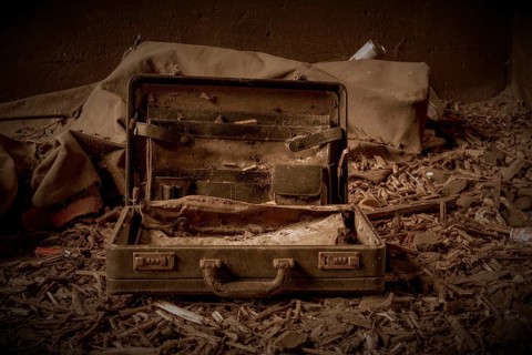 An abandoned, opened suitcase on a dirty floor in a gloomy environment, former railway junction