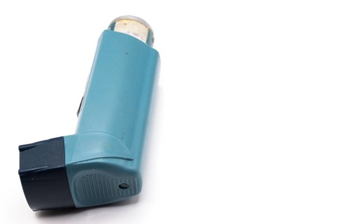 Blue asthma inhaler with blank label isolated on white background. Pharmaceutical product is used