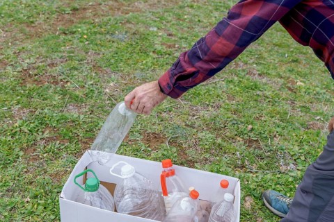 Man collecting empty plastic bottles in the field to recycle, concept of ecology and respect for