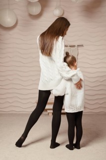 A rear view of a little girl clinging to her mother and hugging her hip