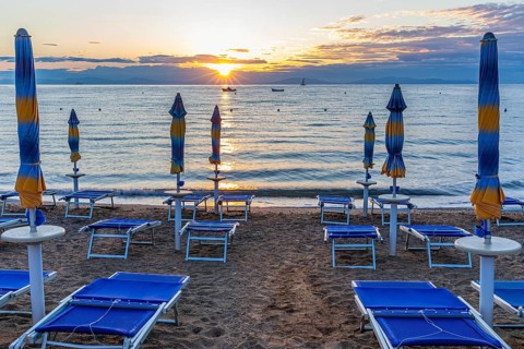 Sun loungers and parasols on Straccolignino beach at sunrise, near Capoliveri, Elba, Tuscan