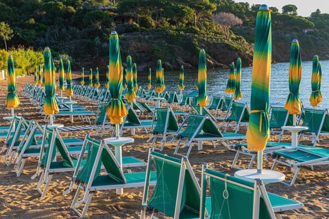 Sun loungers and parasols on Straccolignino beach at sunrise, near Capoliveri, Elba, Tuscan