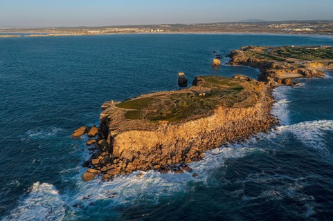 Aerial image of high rocky headland and peninsula. Drone shot of sea blue waves beat and splash in
