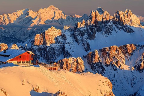 Mountain hut at sunset in the snow in front of rugged mountains, Rifugio Lagazuoi, Dolomites,