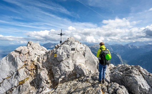 Mountaineer on the rocky summit of the Watzmann Mittelspitze with summit cross, Berchtesgaden