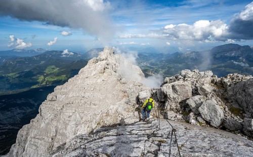 Climber on a via ferrata secured with steel rope, narrow rocky ridge, Watzmann crossing to Watzmann