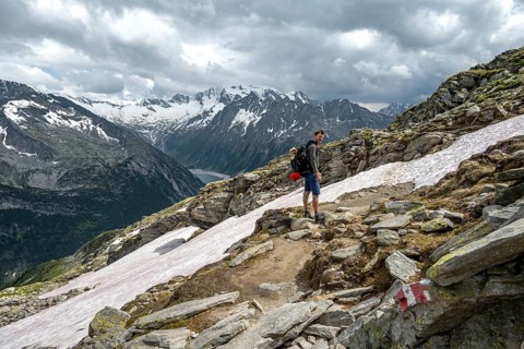 Mountaineer on hiking trail with snow, Berliner Hoehenweg, mountain landscape with glaciated peaks