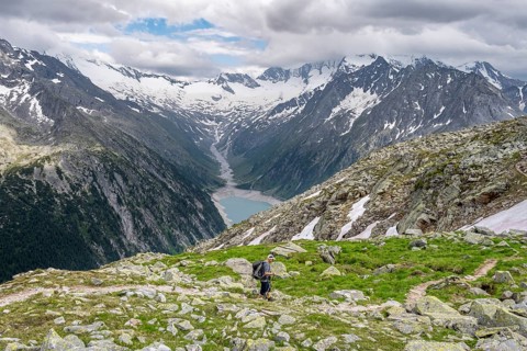 Mountaineer on hiking trail, view of Schlegeisspeicher, glaciated rocky mountain peaks Hoher