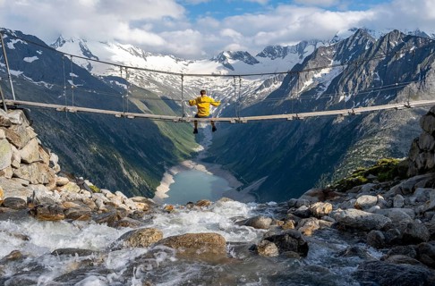 Mountaineer sitting on a suspension bridge over a mountain stream Alelebach, picturesque mountain