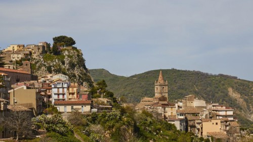 Historic town on a hillside with a striking church tower and nature in the background, Novara di