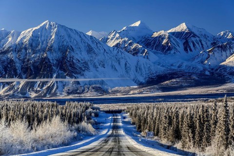 Highway in winter landscape in front of snow-covered mountains, Alaska Highway, Haines Junction,