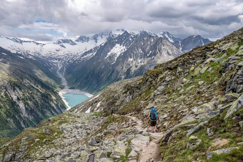 Mountaineer on hiking trail, view of Schlegeisspeicher, glaciated rocky mountain peaks Hoher