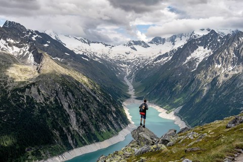Mountaineer on a rock in front of a mountain panorama, view of Schlegeisspeicher, glaciated rocky