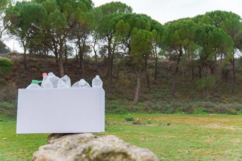 White cardboard box full of empty plastic bottles collected from the field for recycling, in the