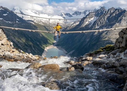 Mountaineer sitting on a suspension bridge over a mountain stream Alelebach, picturesque mountain