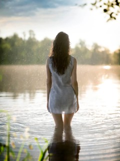 Suicidal thoughts, a young depressive woman with suicidal intent stands in the water by a lake in