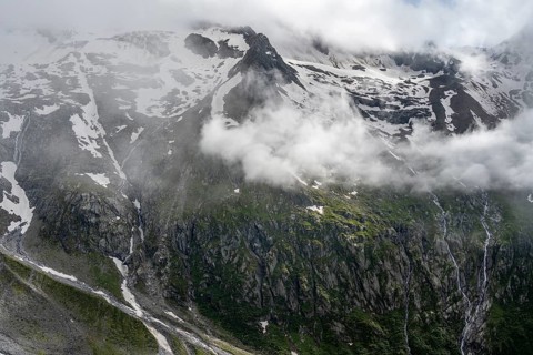 Snow-covered cloudy mountains with Pfitscher ridge and glacier Roetkees, mountain streams as