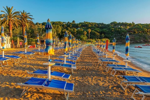 Sun loungers and parasols on Straccolignino beach at sunrise, near Capoliveri, Elba, Tuscan
