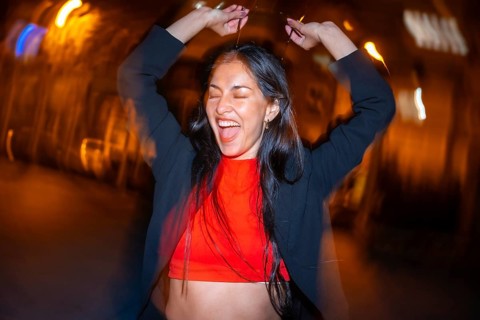 Night photo with flash and motion of an excited woman dancing alone in the city street