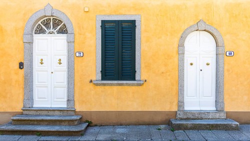 White arched front doors in pastel-coloured house wall, Sant'ilario in Campo, Elba, Tuscan