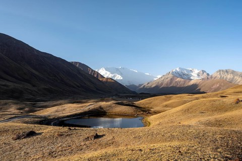 White glaciated and snow-covered mountain peak Pik Lenin at sunrise, mountain landscape with golden